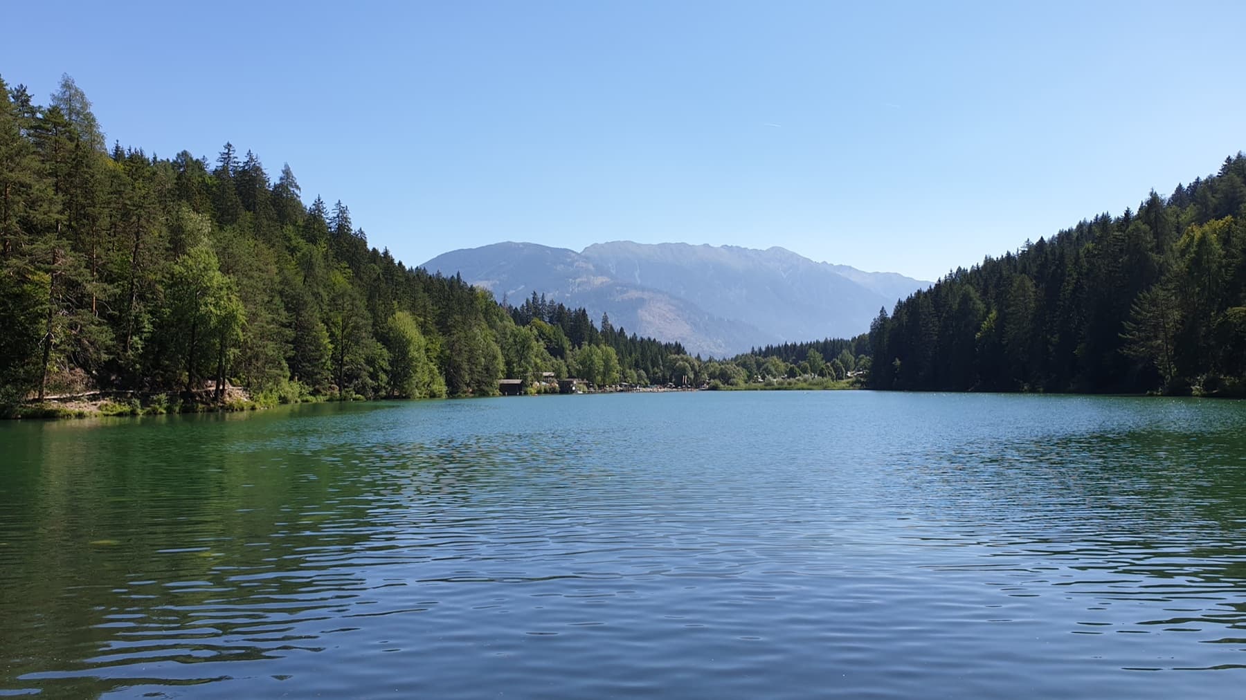 Der Tristacher See, Osttirols einziger Naturbadesee, vor Bergkulisse
